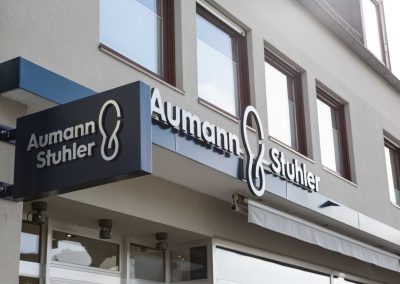 Vordachverkleidung mit Leuchtschrift und Fahnenschild